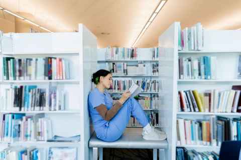 Woman sitting between library shelves 